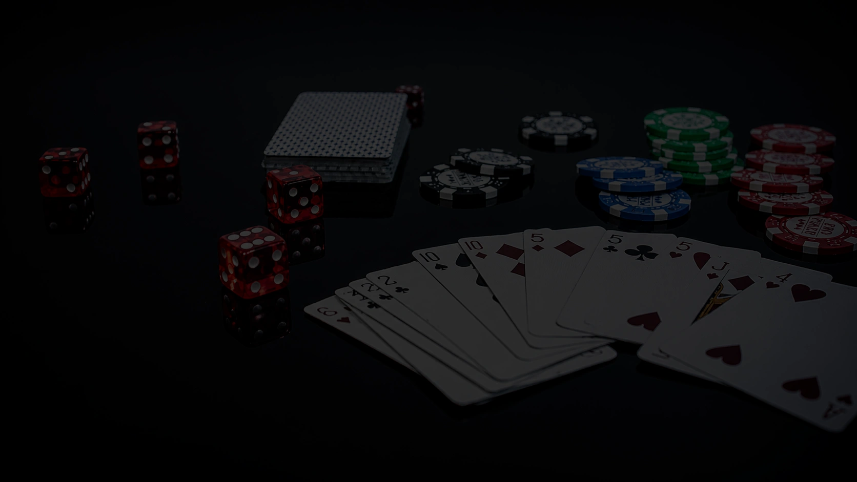 Dark poker table scene with playing cards dice and stacked chips on black background